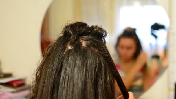 Een meisje doet een haarsnit door een haren ijzer. — Stockvideo