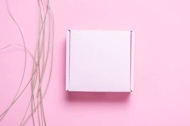 Kurumuş çimenlerle süslenmiş pembe karton kutu..