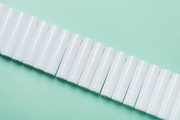 Mavi Arka Planda Bir Sürü Beyaz Plastik Dudak Parlatıcı Tüpü — Stok fotoğraf