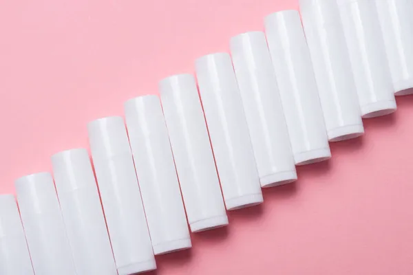 Pembe Arka Planda Bir Sürü Beyaz Plastik Dudak Parlatıcı Tüpü — Stok fotoğraf