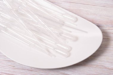 Bir sürü plastik tek kullanımlık boru, alet, ahşap masa.