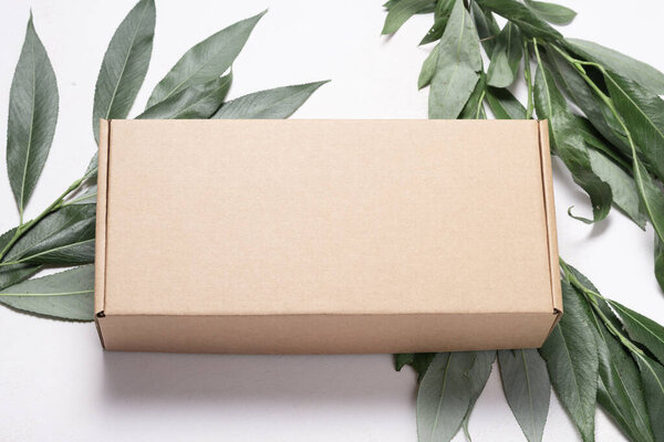 Бурый картонный ящик на белом деревянном фоне