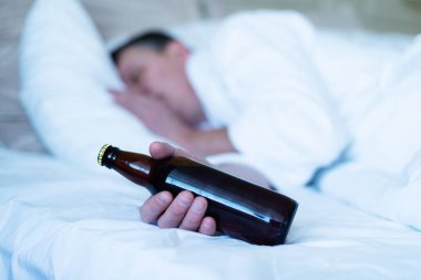 Uyuyan adam elinde ayı şişesi, alkolik.