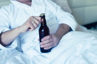 Yatakta ayı şişesi açan adam alkolik.