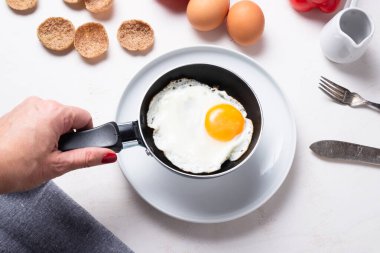 Mutfak masasında küçük bir tavayı tutan kadın.