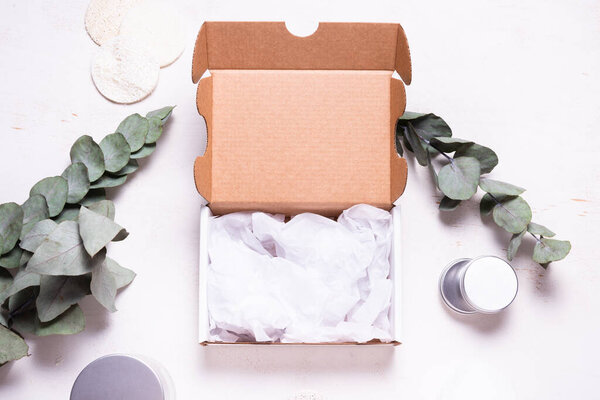 Картонная коробка белого цвета, украшенная зеленым эвкалиптом