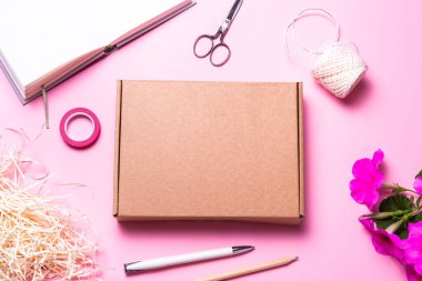 Brown cardboard, carton box on pink background decorated with re