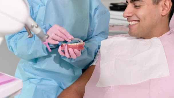 Orthodontist met onzichtbare beugel voor het uitlijnen van tanden. In de kliniek toont patiënt moderne tandheelkundige technologie - verwijderbare transparante plastic uitlijnapparaten of invisalign gebruik en voordeel. — Stockvideo