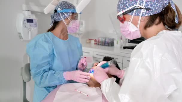 Dentysta stosujący lampę UV utwardzającą zęby pacjenta podczas napełniania. Koncepcja medycyny, stomatologii i opieki zdrowotnej. — Wideo stockowe