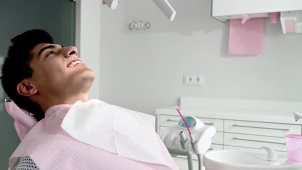 Πορτραίτο ενός θετικού όμορφου ασθενή που χαμογελά κοιτάζοντας την κάμερα, μετά τη θεραπεία στην οδοντιατρική κλινική. — Αρχείο Βίντεο