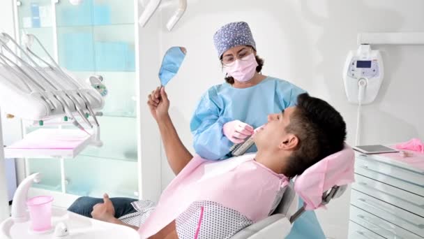 Pacjent patrzący w lustro w klinice dentystycznej — Wideo stockowe