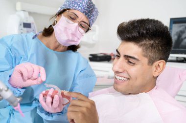 Dişçi görünmez diş tellerinin hizalandığını gösteriyor. Bir ortodontik kliniğinde diş muayenesi. Yüksek kalite fotoğraf.