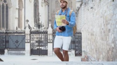 Haritalı bir turist sokakta yürüyor ve eski anıtlara bakıyor. Yüksek kalite 4k görüntü