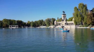 Madrid, İspanya 'da güneşli bir günde, Parque del Buen Retiro gölündeki teknelerde turistler.