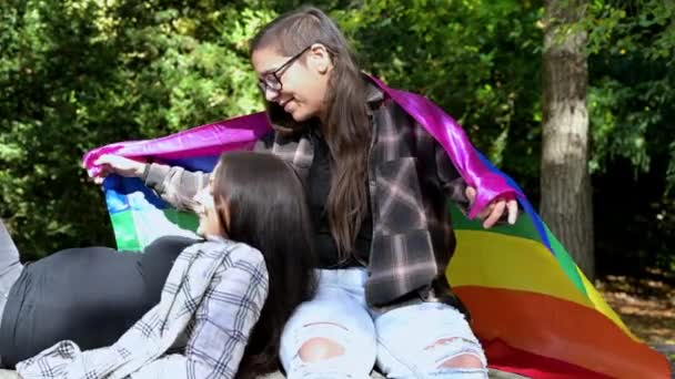 Joven pareja lesbiana cariñosa descansando en el parque en un banco tiernamente besándose. — Vídeos de Stock