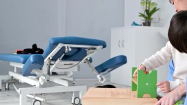 Terapist, özürlü küçük çocukla gelişim faaliyetleri yapıyor. Beyin felci geçirmiş bir çocuk rehabilitasyon, öğrenme, gelişme. Tıp merkezinde eğitim.