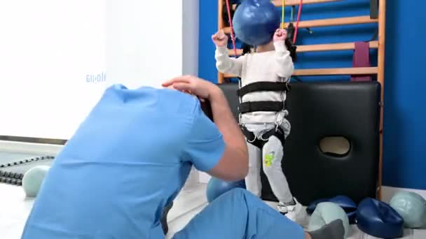 Lindo niño con discapacidad haciendo terapia musculoesquelética mediante ejercicios en el hospital mientras ríe y se divierte . — Vídeos de Stock
