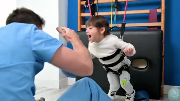 Aranyos gyerek fogyatékossággal csinál mozgásszervi terápia által gyakorlatok a kórházban, miközben nevet és szórakozás . — Stock videók