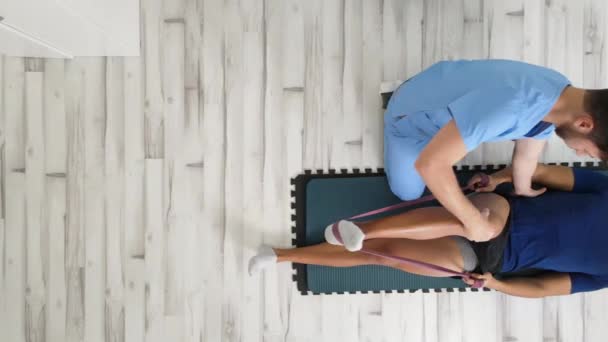 Vista aérea de un terapeuta que ayuda a un paciente masculino mientras estira su pierna en el hospital — Vídeos de Stock