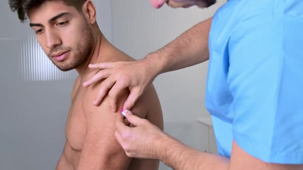 Fisioterapeuta aplicando cinta de kinesio en el hombro del paciente masculino. Kinesiología, fisioterapia, concepto de rehabilitación. de cerca — Vídeo de stock
