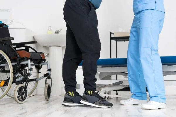 Male Physiotherapist helping a patient with a disability who uses a wheelchair, to get up at rehabilitation hospital. — Stock Photo, Image