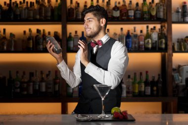 Havalı profesyonel barmen kokteyl hazırlıyor, kokteyl karıştırıyor. Modern barda içki yapan otantik barmen..