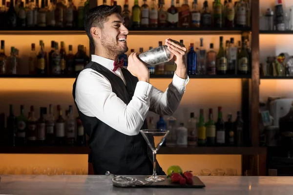 Прохолодний професійний бармен робить коктейль, трясе коктейль шейкером. Справжній бармен, що робить алкогольні напої в сучасному барі . — стокове фото