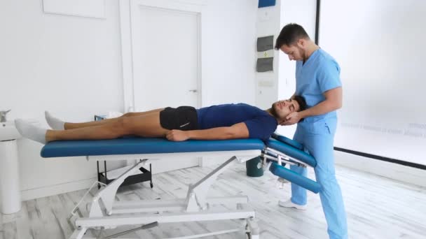 Fisioterapeuta massagear o pescoço de um paciente jovem, zoom em dolly shot suave. — Vídeo de Stock
