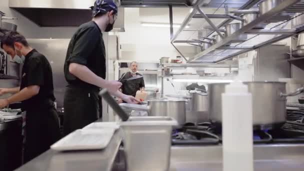 Verschiedene Köche bereiten in der Restaurantküche Speisen zu. Arbeiten in einer belebten Restaurantküche. — Stockvideo