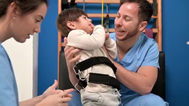 Fisioterapeutas Preparación de un niño con discapacidad para el tratamiento de rehabilitación en el hospital. — Vídeos de Stock