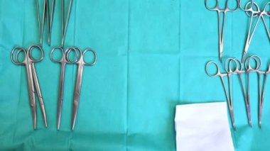 Mavi masanın üstünde birden fazla ameliyat aleti var. Cerrah masadan cerrahi aletleri alır..