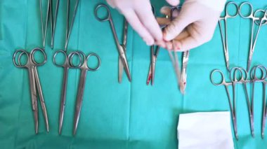 Mavi masanın üstünde birden fazla ameliyat aleti var. Cerrah masadan cerrahi aletleri alır..