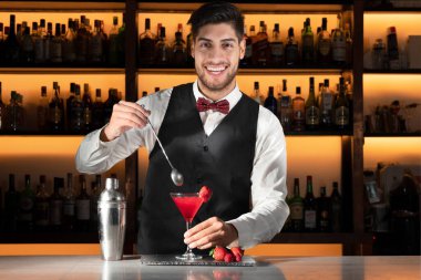 Genç barmen gece kulübünde kokteyl servisi yapıyor..