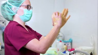 Hayvan hastanesinde ameliyata başlamadan önce ellerini yıkayan veteriner cerrahı..