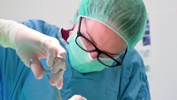 Close-up portret van een vrouwelijke chirurg in steriele kleding opererend in de operatiekamer. — Stockvideo