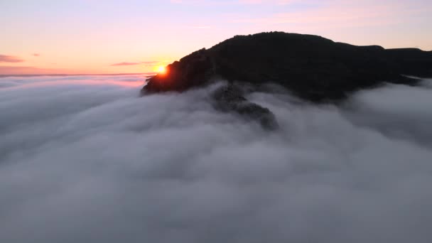 Zdjęcie lotnicze majestatycznego wschodu słońca w górach. Dolina pomiędzy górami jest pokryta mgłą i oświetlona ciepłymi promieniami wschodzącego słońca. — Wideo stockowe