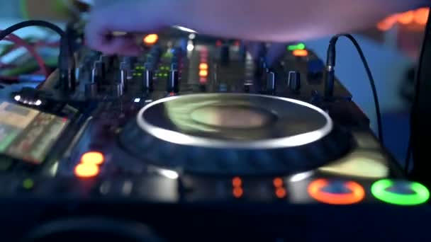 Tracking shot of a Man DJ playing with mixer and digital turntables. CDJ turntables with wires, button and sliders being played by electronic music Disc Jockey at nightclub. — Video Stock