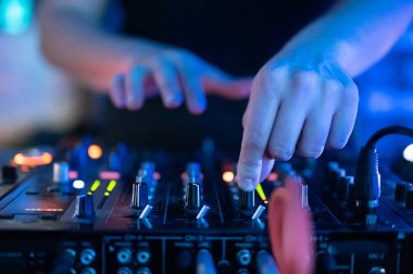 DJ ellerinin bir gece kulübünde müzik masasını kontrol edişinin ön görüntüsünü kapat.