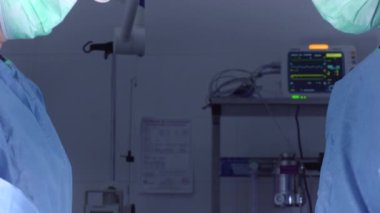 Ameliyathanede parlak ışık altında dururken tıbbi üniformalı kadın cerrahların görüntülerini yukarı kaldır.