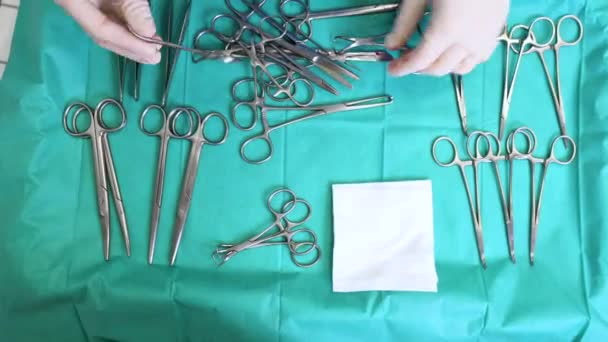 Несколько хирургических инструментов на синем столе над обзором. хирург берет хирургические инструменты со стола. — стоковое видео