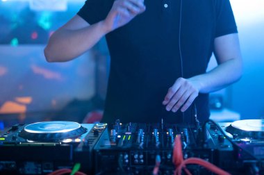 DJ ellerinin bir gece kulübünde müzik masasını kontrol edişinin ön görüntüsünü kapat.