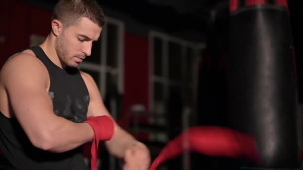 Handsome caucasian boxer wrapping his hands with a band, preparing himself in boxing arena sport — Stock Video