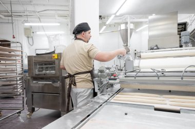 Fırında çalışan fırıncı tepsileri taze somunla hazırlıyor.. 