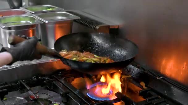 コックインシェフのスローモーションは、キッチンで働きます。レストラン鍋火料理を閉じる,商業キッチンで野菜炒めを調理します。. — ストック動画