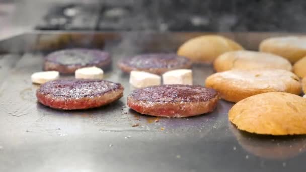 Închiderea patties burger flipping și chifle de încălzire pe o griddle la o articulație burger. — Videoclip de stoc