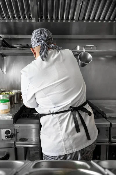 Back view of woman chef cooking food in the kitchen of a restaurant. — Stock Photo, Image