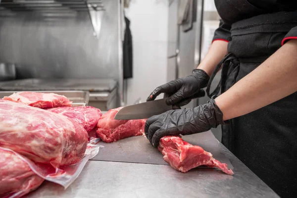Close up of raw meat and woman butcher cutting meat with knife. — Stock Photo, Image