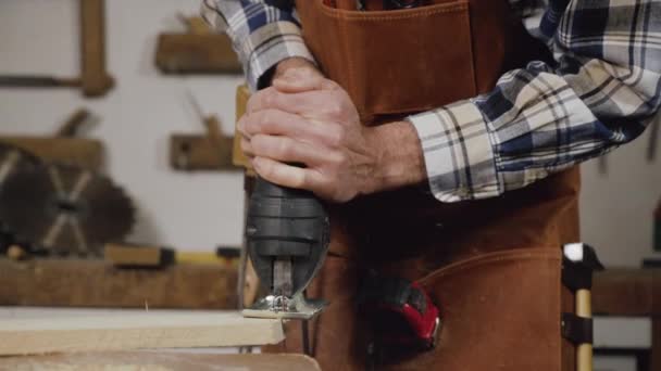 Ο ξυλουργός πριονίζει μια ξύλινη σανίδα με ηλεκτρικό πριόνι σε εργαστήριο ξυλουργικής. Έννοια DIY ξύλου εργασίας — Αρχείο Βίντεο