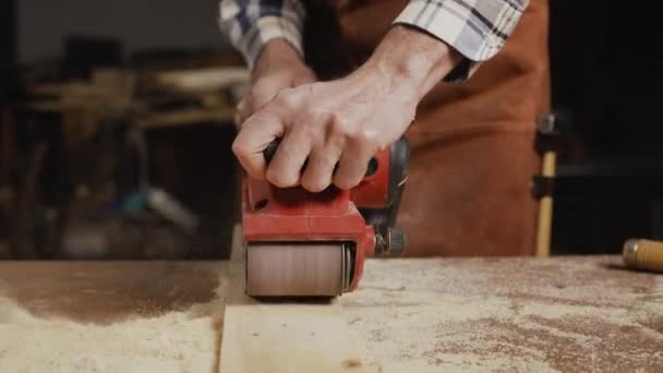 Ponçage du bois de menuisier avec ponceuse à courroie à l'atelier dans un projet de planche de bois ou menuiserie — Video