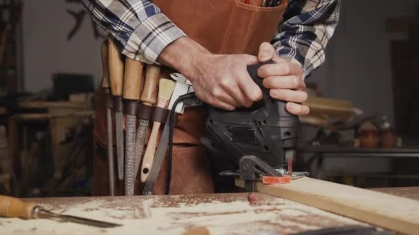 Timmerman zaagt een houten plank met elektrische decoupeerzaagmachine in timmerwerkplaats. Werkwood DIY-concept — Stockvideo